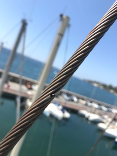 Câble de marin au premier plan, avec un port et des bateaux en arrière-plan.